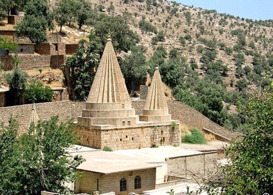 The conical spires of the Lalish temple among trees on a hillside